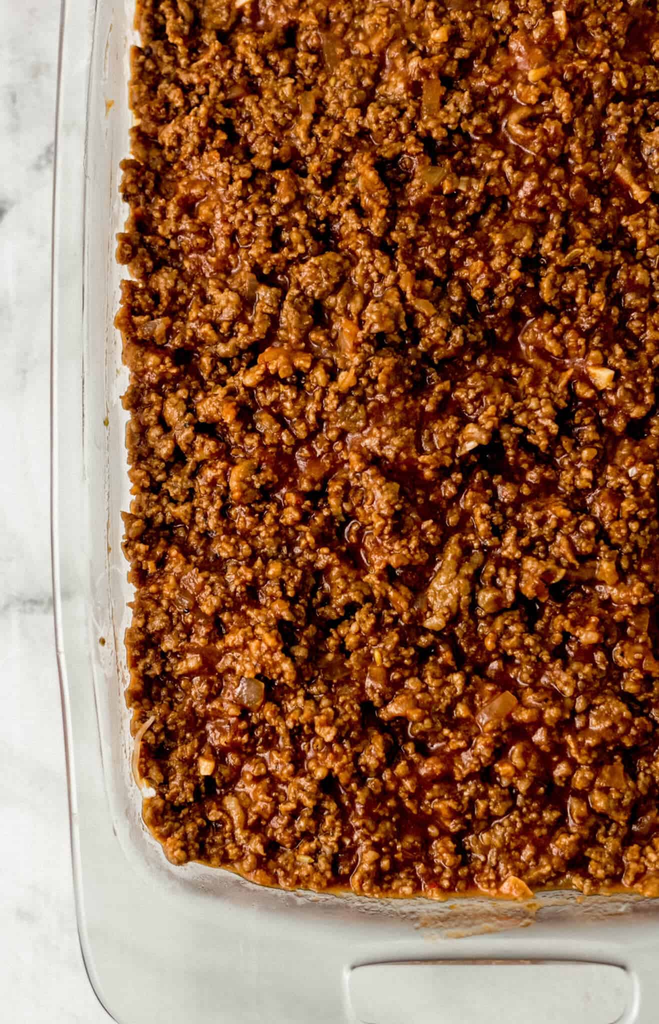 meat sauce added to baking dish on top of spaghetti and cheese