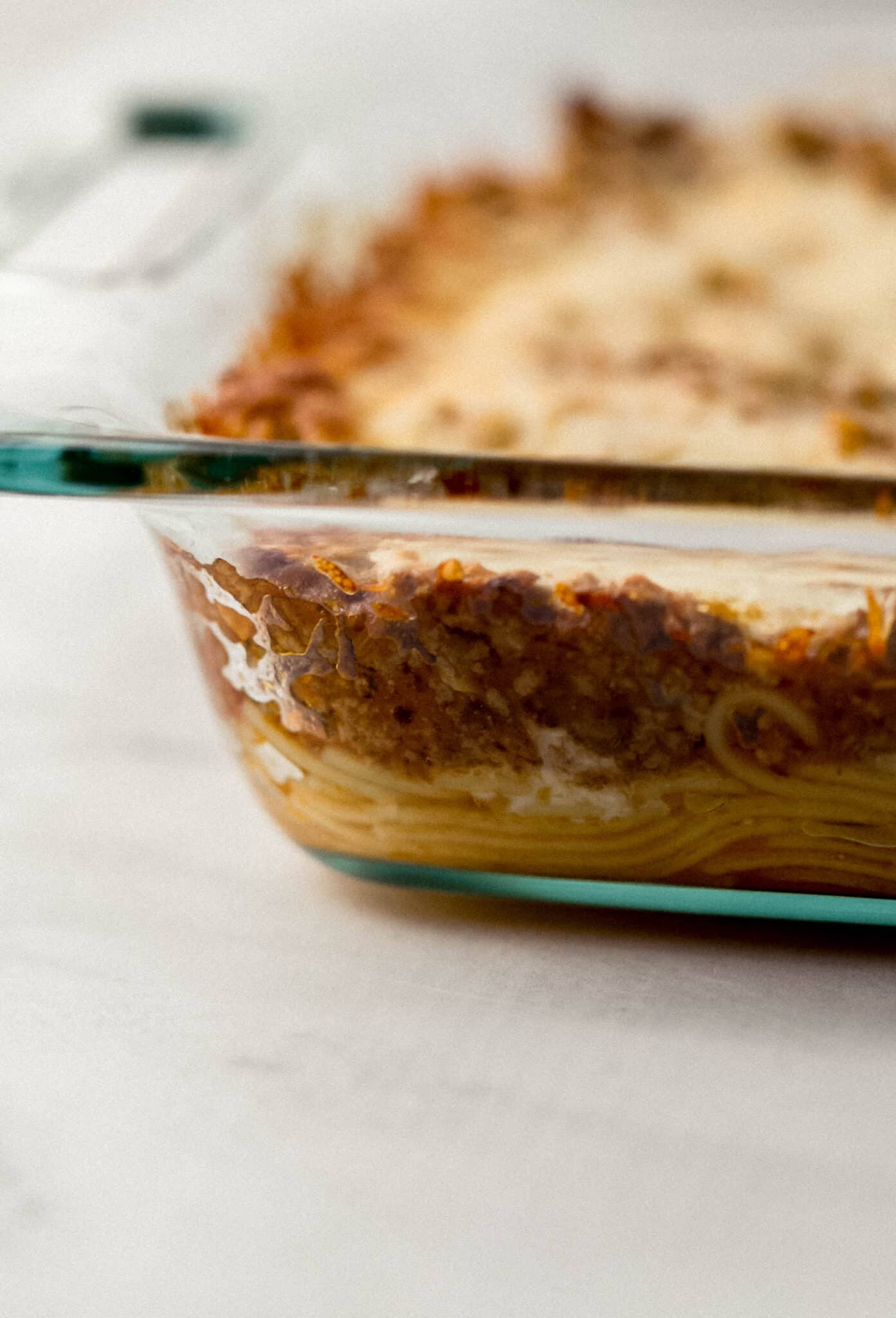 close up side view of finished baked spaghetti in glass baking dish 