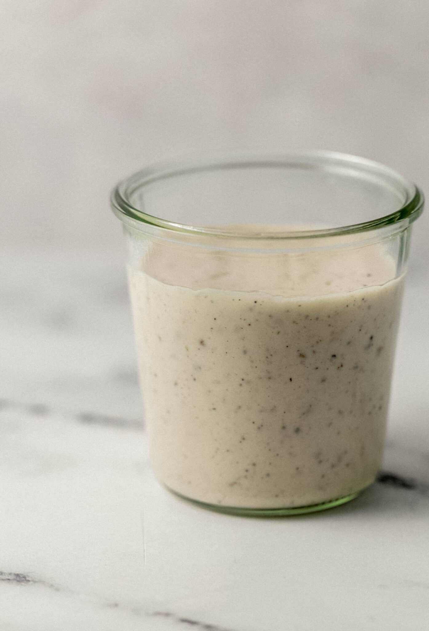 close up side view of gravy in a glass jar 