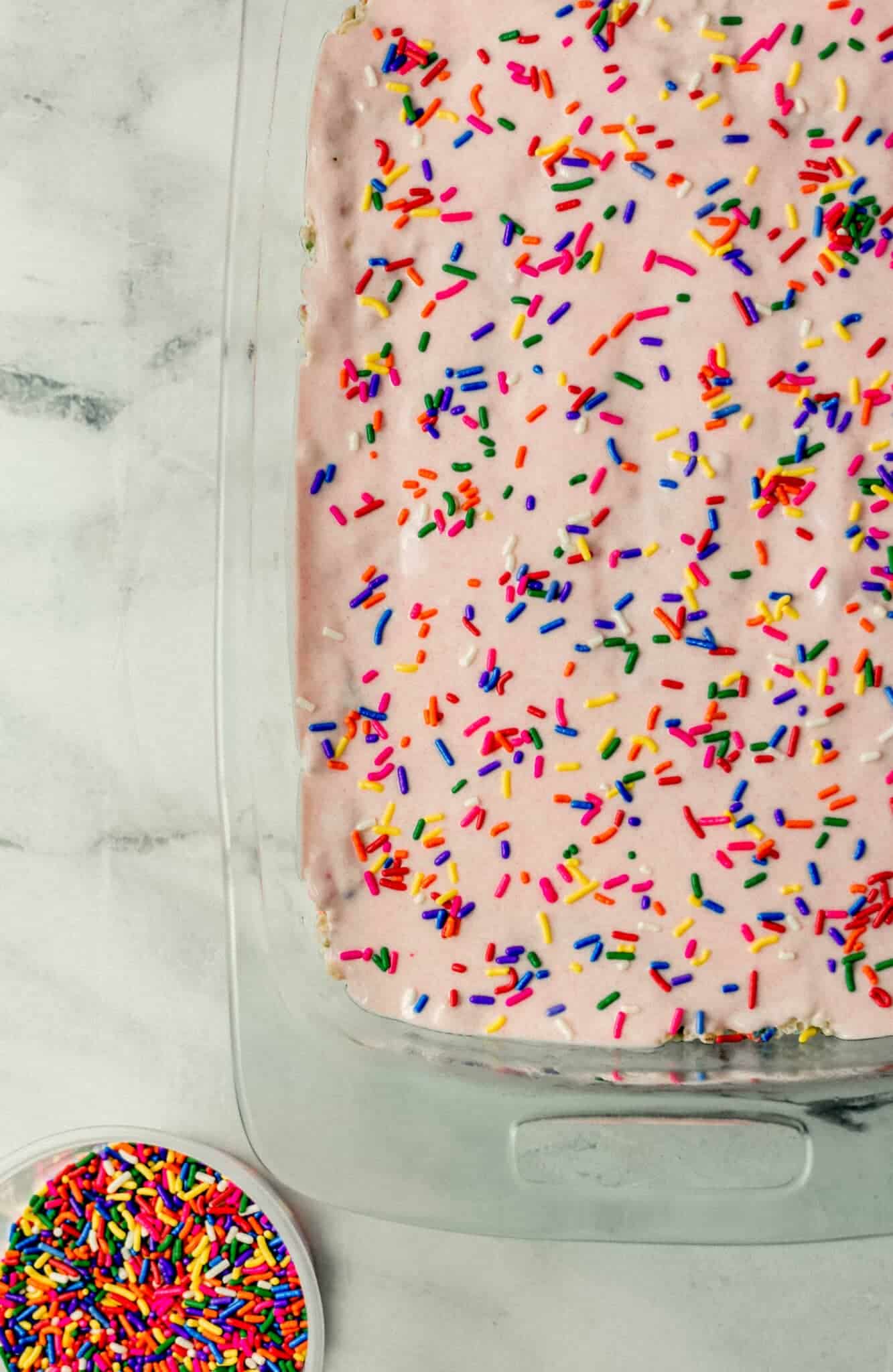 rice krispie treats topped with white chocolate mixture and sprinkles