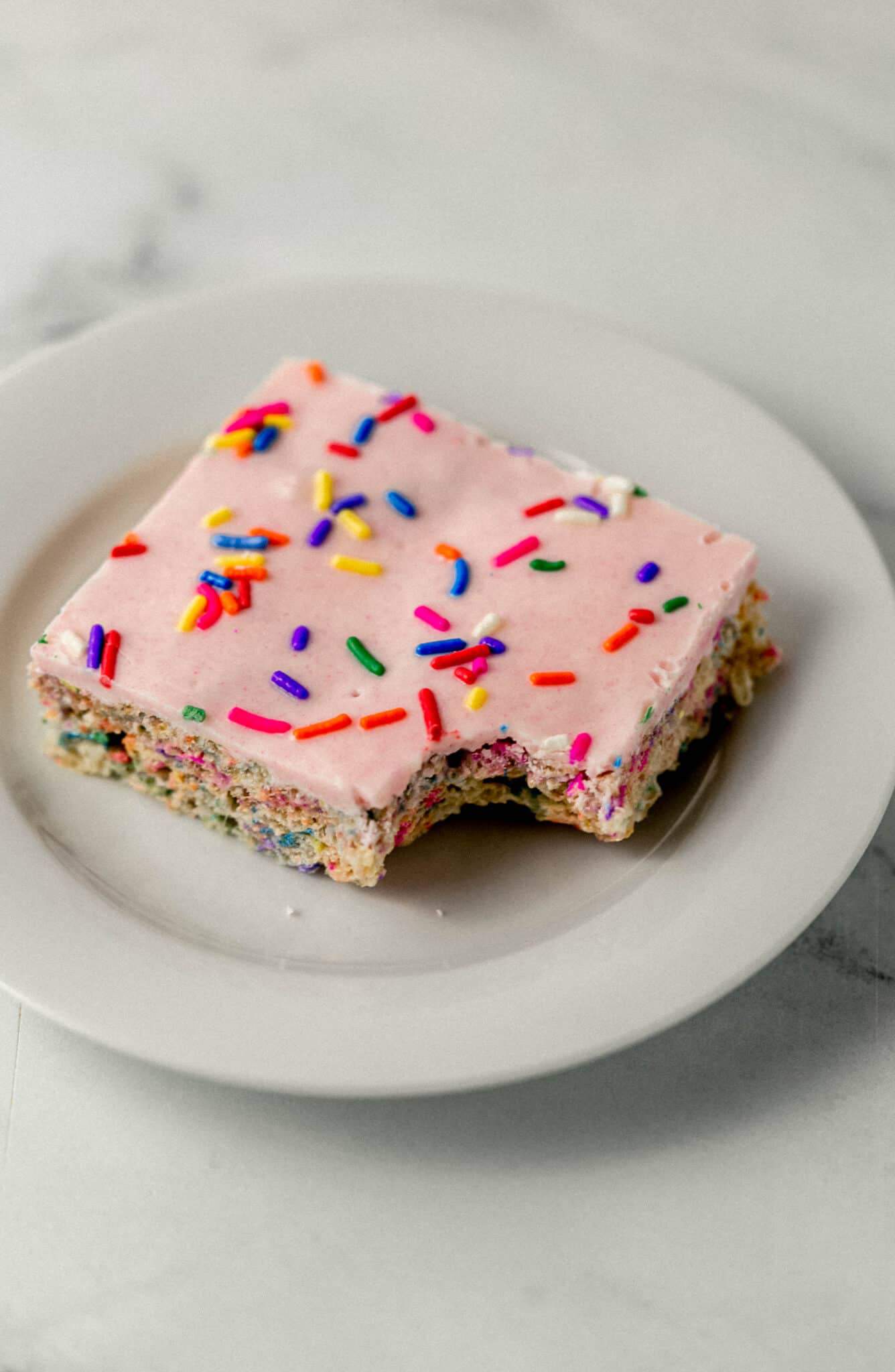 single rice krispie treat on white plate with a bite in it 