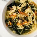 Close up overhead view of serving of soup in white bowl on marble surface.