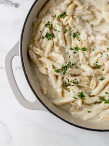 finished pasta in large pan topped with parsley and grated Parmesan