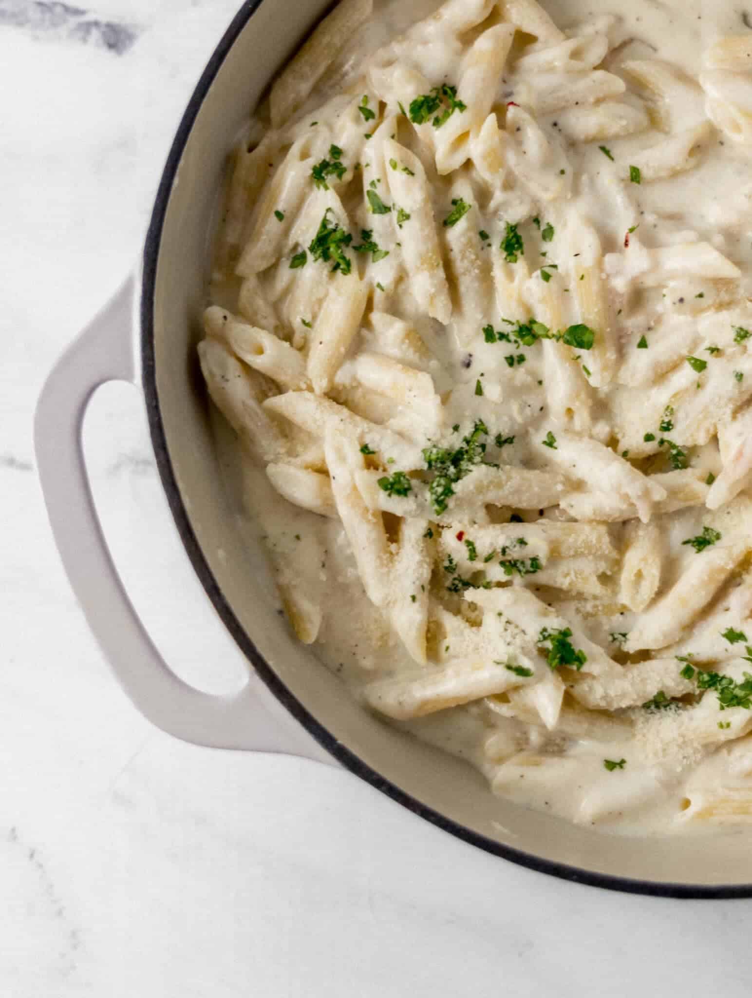 overhead view of finished pasta in pan topped with parsley and parmesan cheese