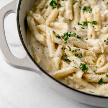 close up side view of finished pasta in pan topped with parsley and grated parmesan cheese