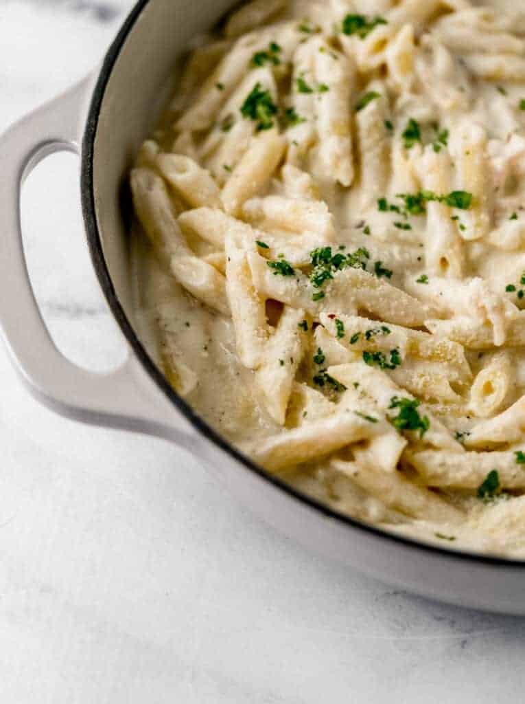close up side view of finished pasta in pan topped with parsley and grated parmesan cheese