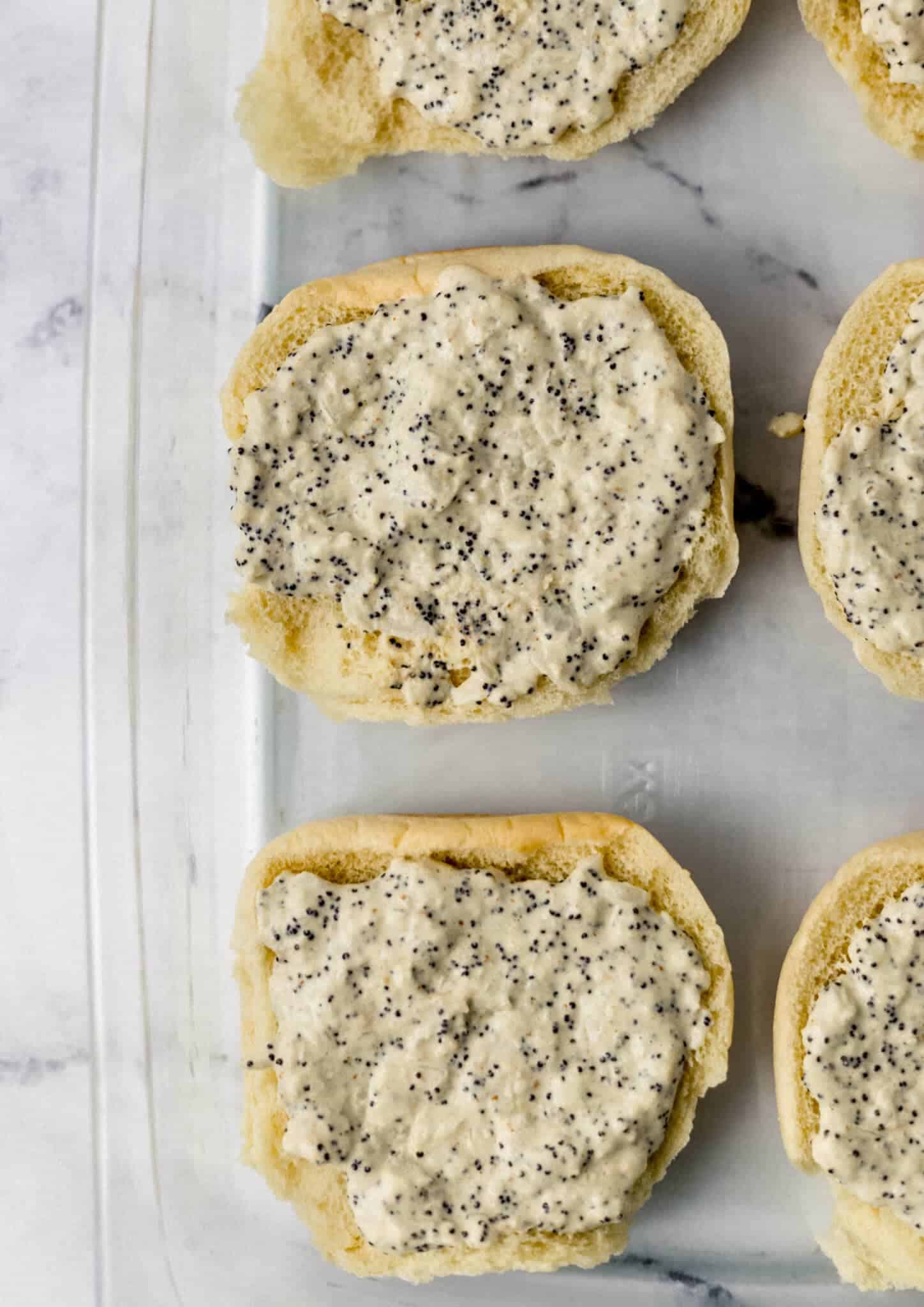 overhead view of sauce spread on buns in glass baking dish 