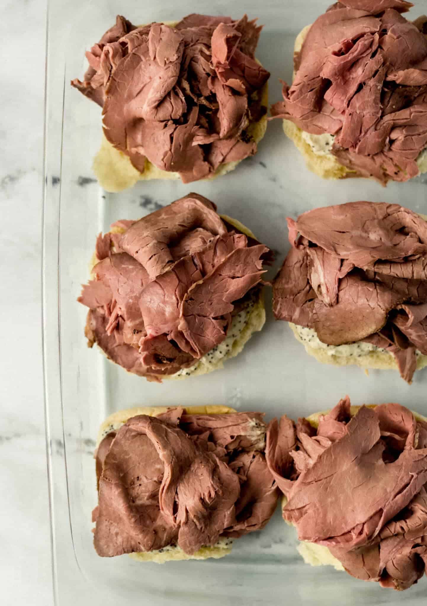 roast beef added to buns in glass baking dish 