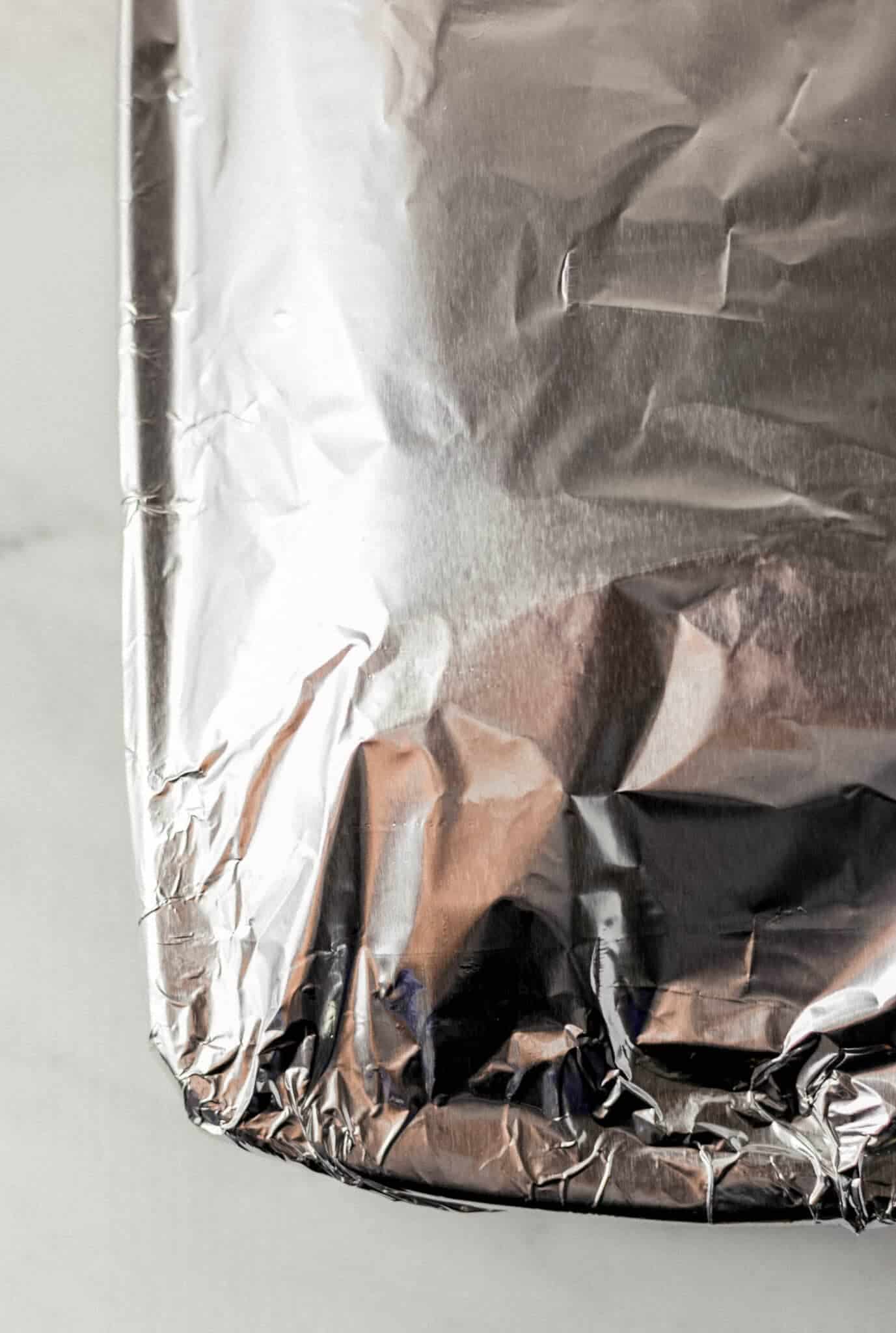 glass baking dish with sandwiches in it covered with aluminum foil before baking 