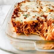 Close up front view of finished spaghetti in glass baking dish with some out of it.
