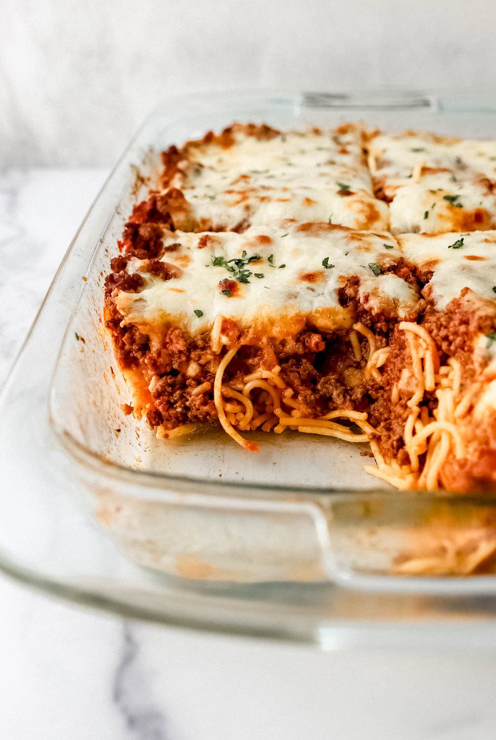 Close up view of front view of spaghetti in glass baking dish. 