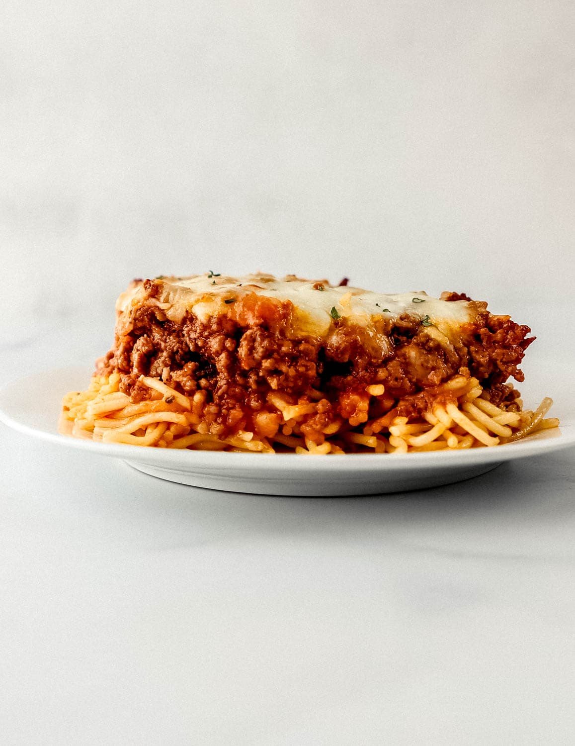 Close up side view of piece of finished spaghetti on white plate. 