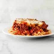 SIde view of piece of spaghetti on a white plate.