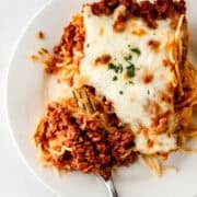Overhead view of piece of spaghetti on plate with fork in it.