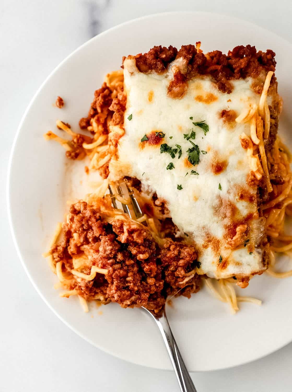 Piece of spaghetti on plate with fork in it. 
