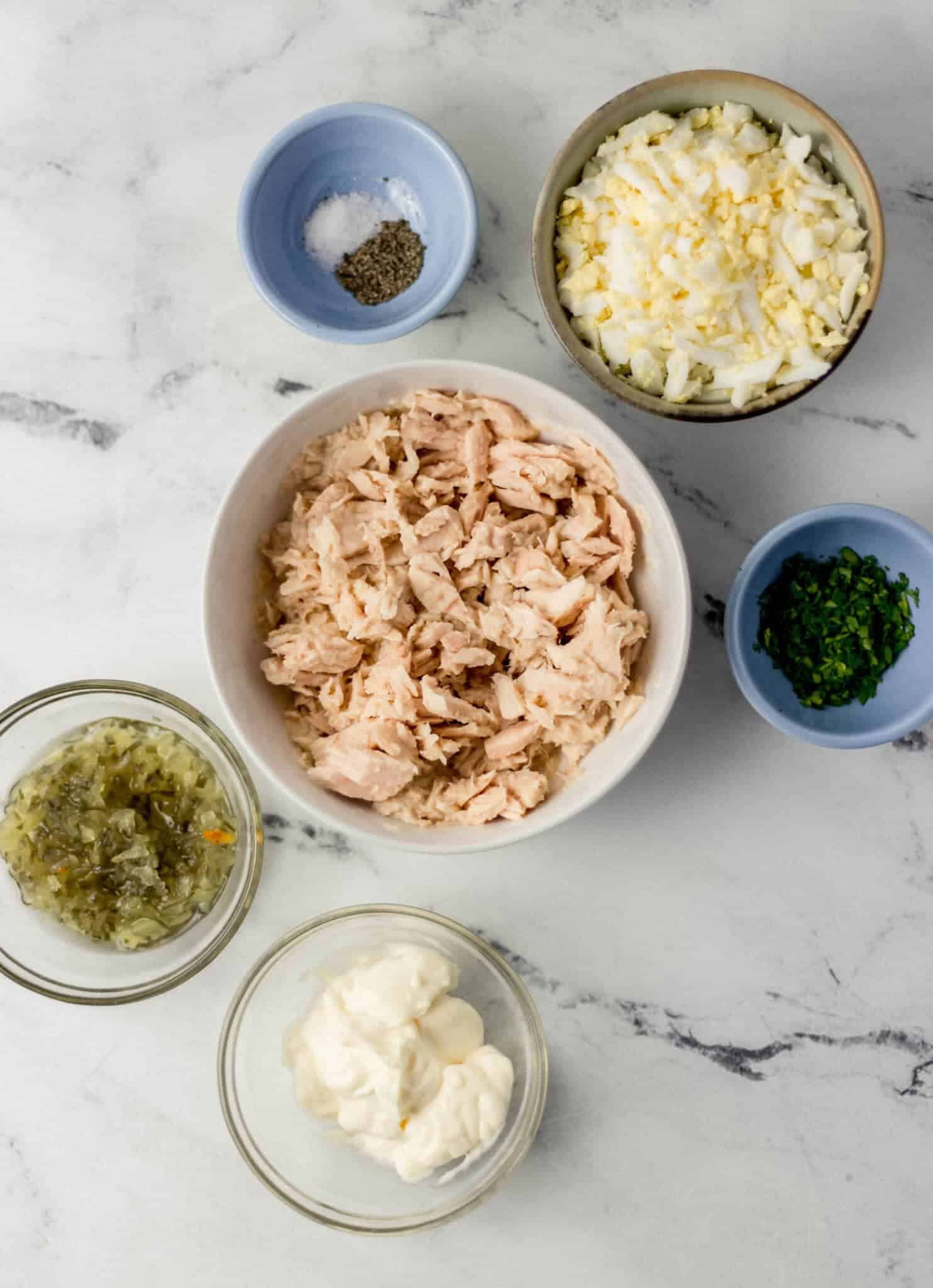 ingredients needed to make tuna salad in separate bowls 