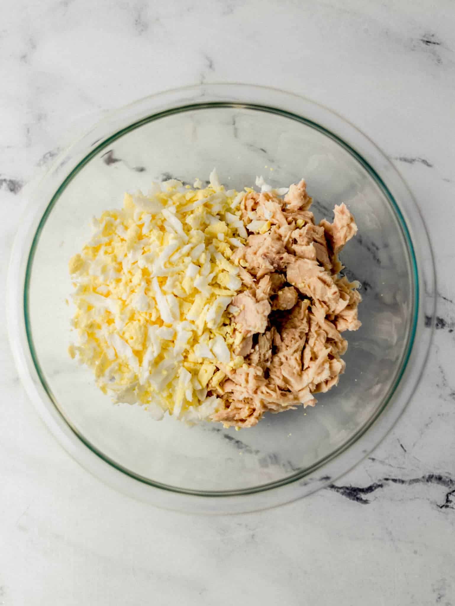tuna and grated eggs added to glass mixing bowl 