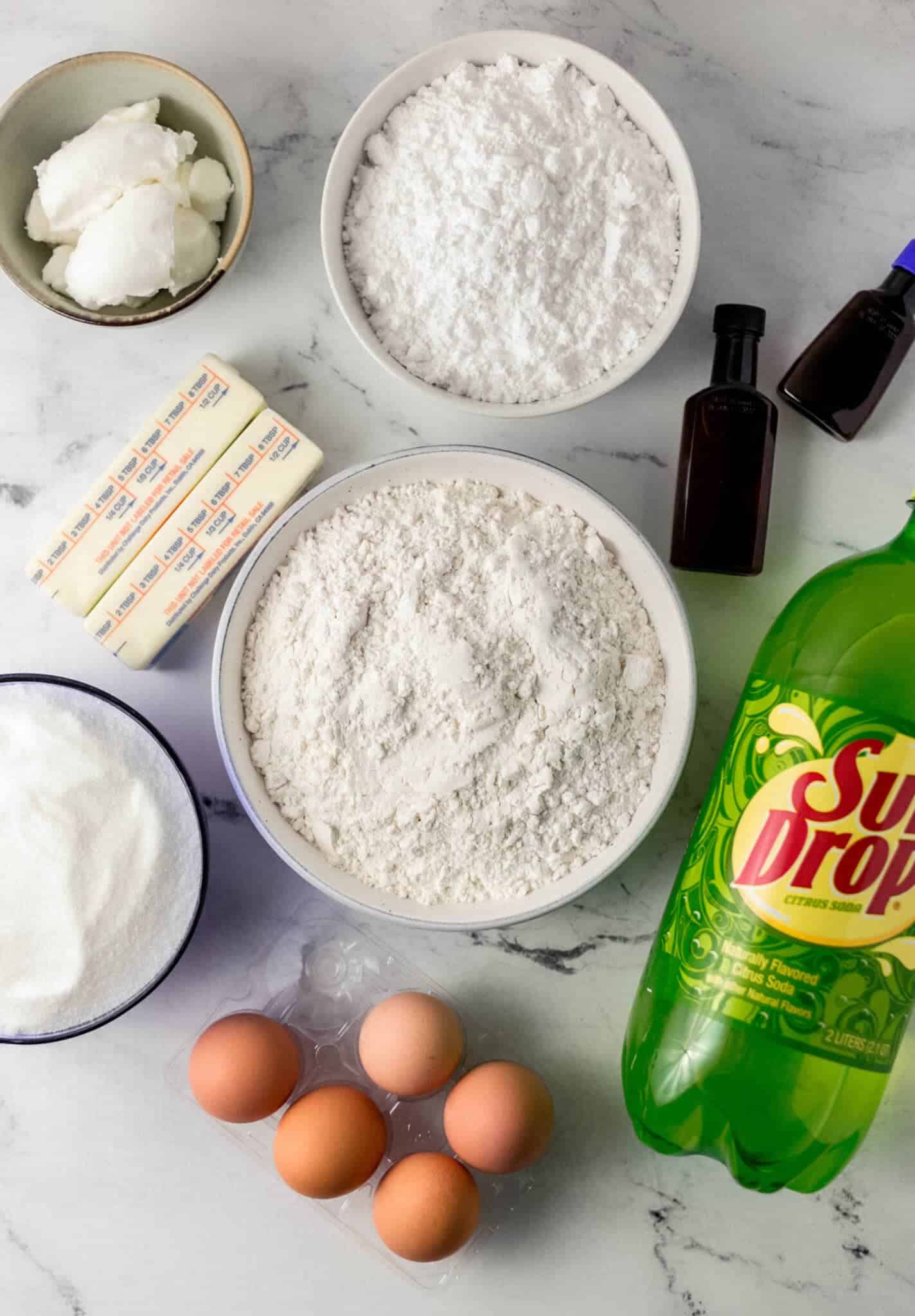 ingredients needed to make cake in separate containers on marble surface 