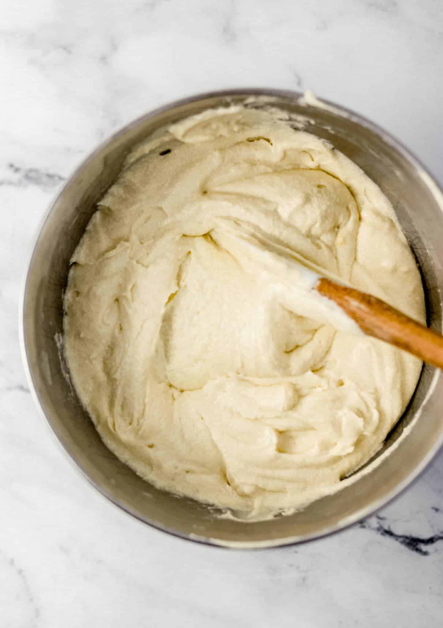 all cake ingredients combined in stand mixer bowl with rubber spatula 