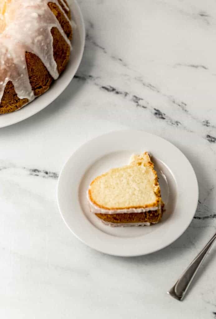 overhead view of slice of cake on a small white plate by a fork and the rest of the cake