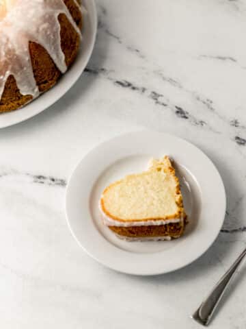 overhead view of slice of cake on a small white plate by a fork and the rest of the cake