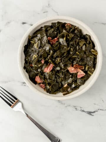 overhead view of finished white bowl of southern collard greens recipe with ham hocks