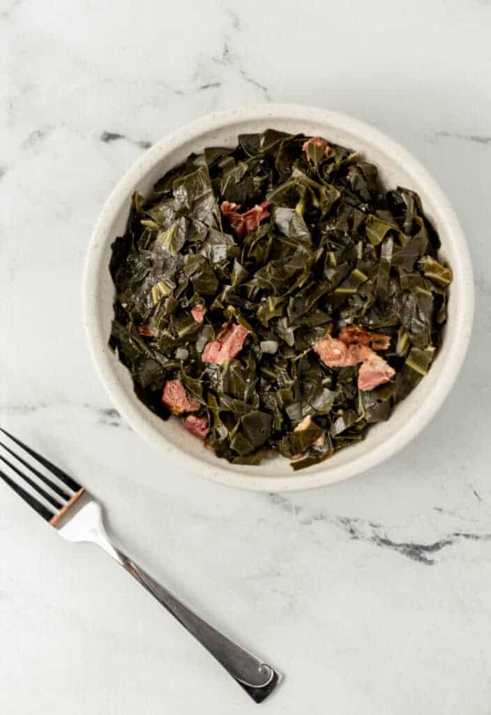 overhead view of finished white bowl of southern collard greens recipe with ham hocks