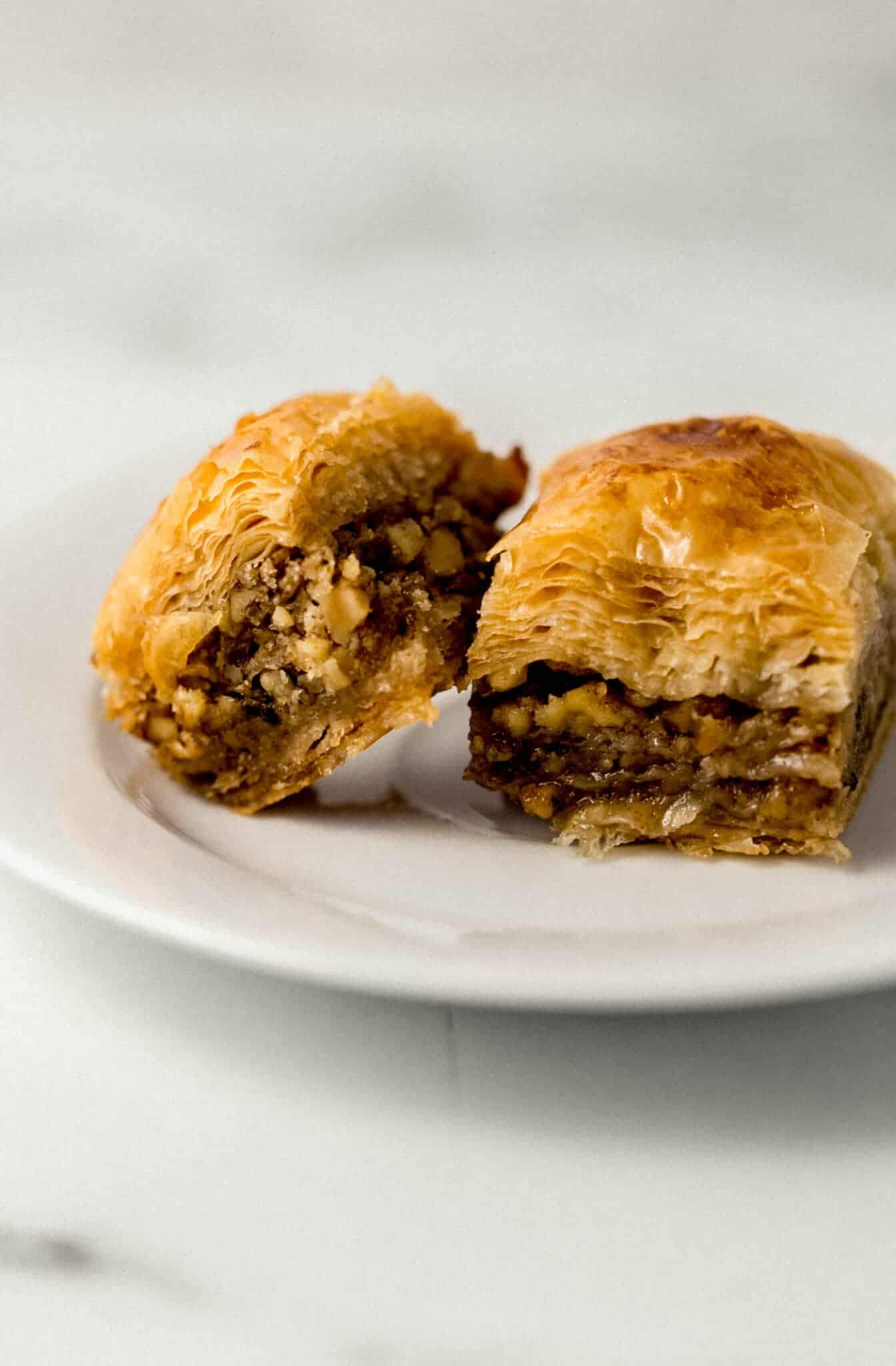 close up side view of two pieces of baklava on small white plate 