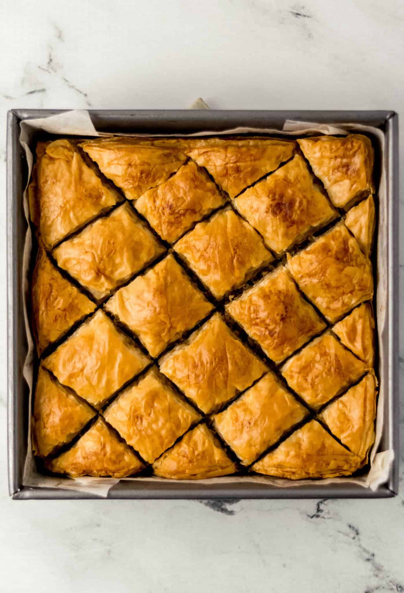 freshly baked baklava in parchment lined baking pan 