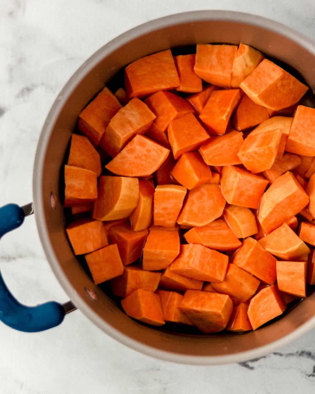Overhead view of cut up sweet potatoes in a large pot. 