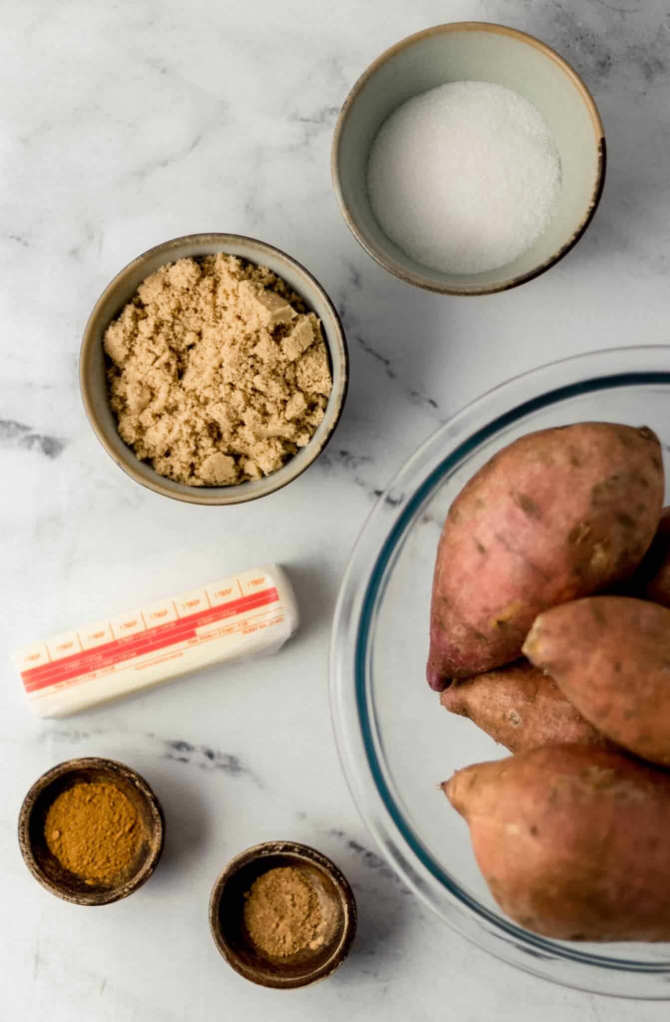 overhead view of ingredients needed to make yams in separate bowls along with a stick of butter 