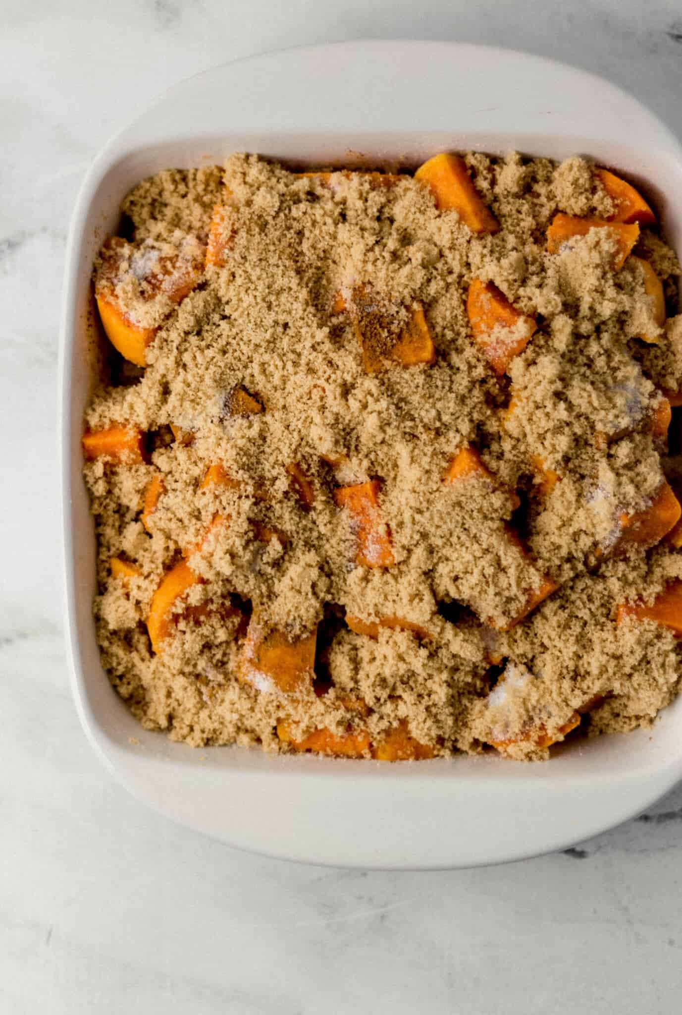 granulated sugar and brown sugar added to sweet potatoes in baking dish 