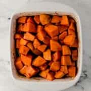 overhead view of finished candied yams in white square baking dish on marble surface