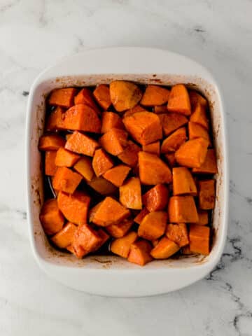 overhead view of finished candied yams in white square baking dish on marble surface