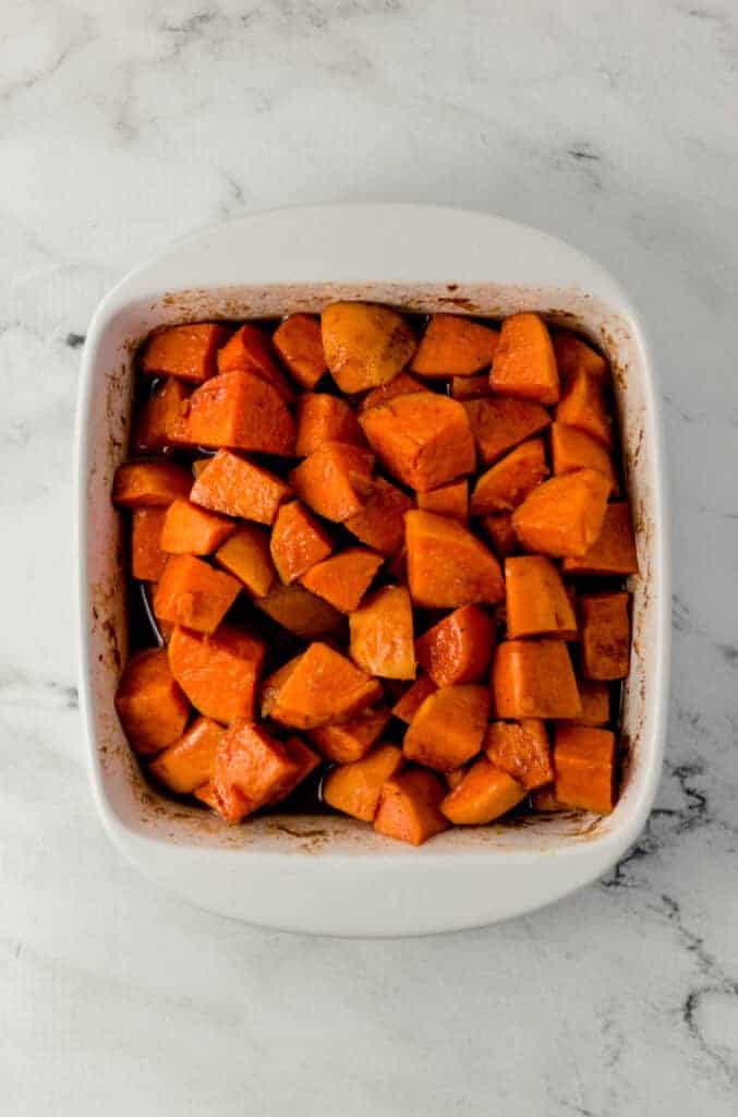 overhead view of finished candied yams in white square baking dish on marble surface