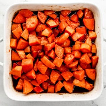 Overhead view of finished candied yams in square white baking dish on marble surface.