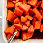 Close up view of yams in baking dish with serving spoon in it.