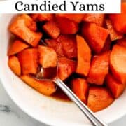 Serving of finished yams in white bowl with spoon on pin with text overlay.