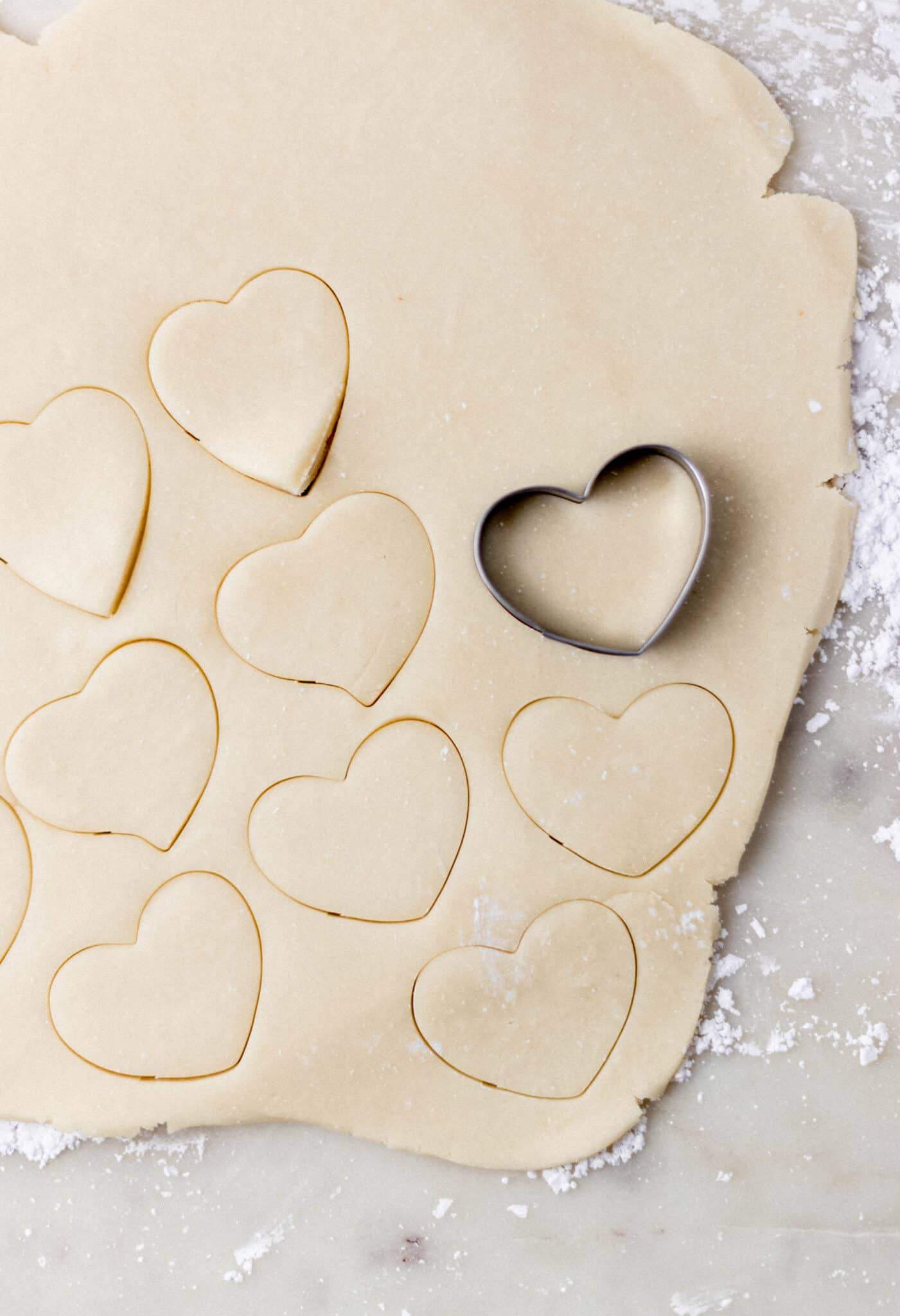 cookie dough rolled out and cookies cut out with heart shaped cutter 