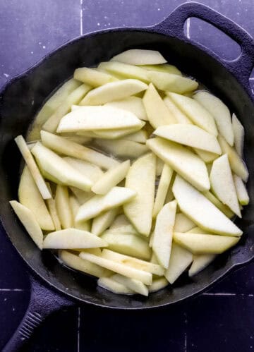 Sliced apples and butter added to a cast iron skillet.