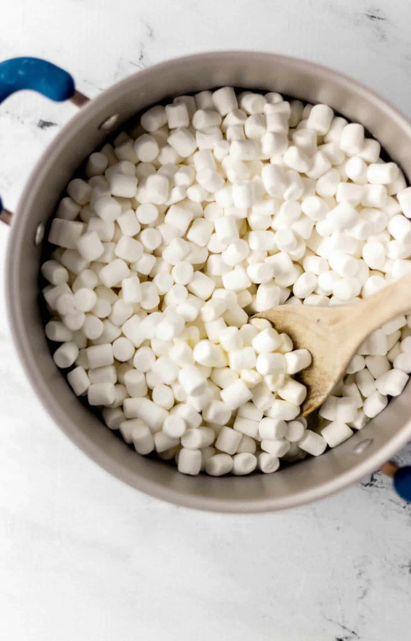 mini marshmallows, butter, and vanilla added to large pot with wooden spoon