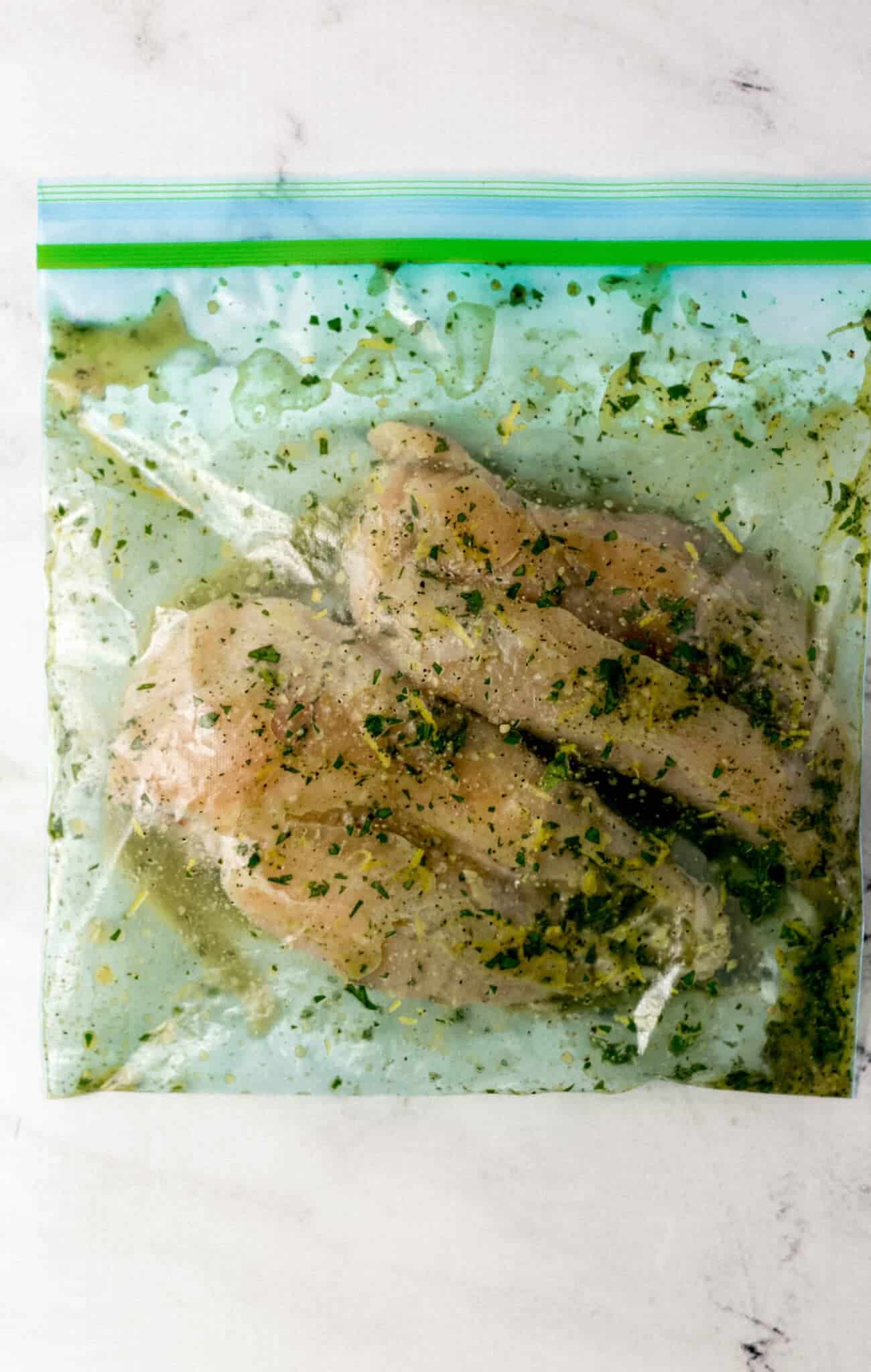 raw chicken and marinade inside a plastic bag 