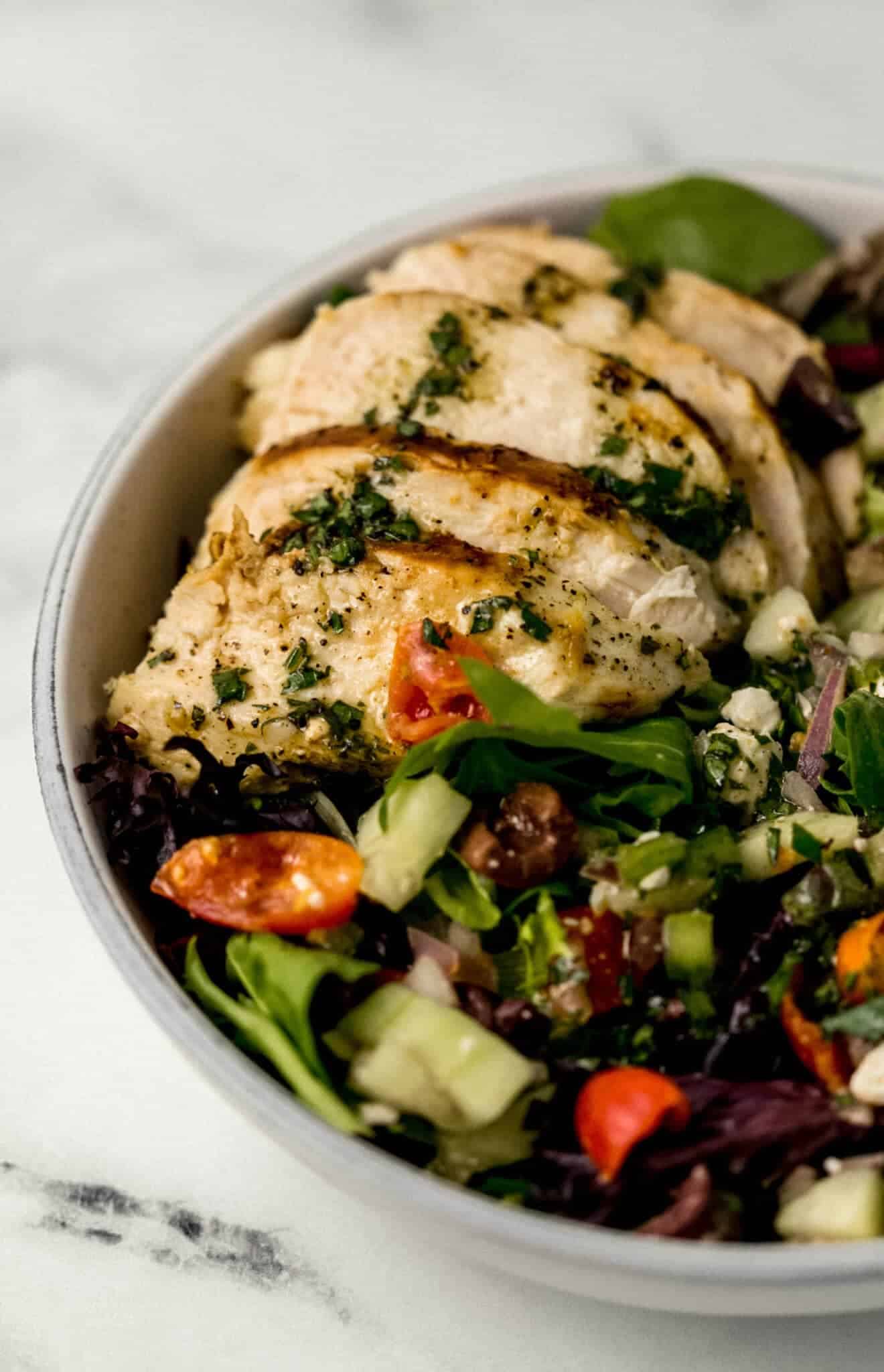 close up view of finished salad topped with sliced chicken 