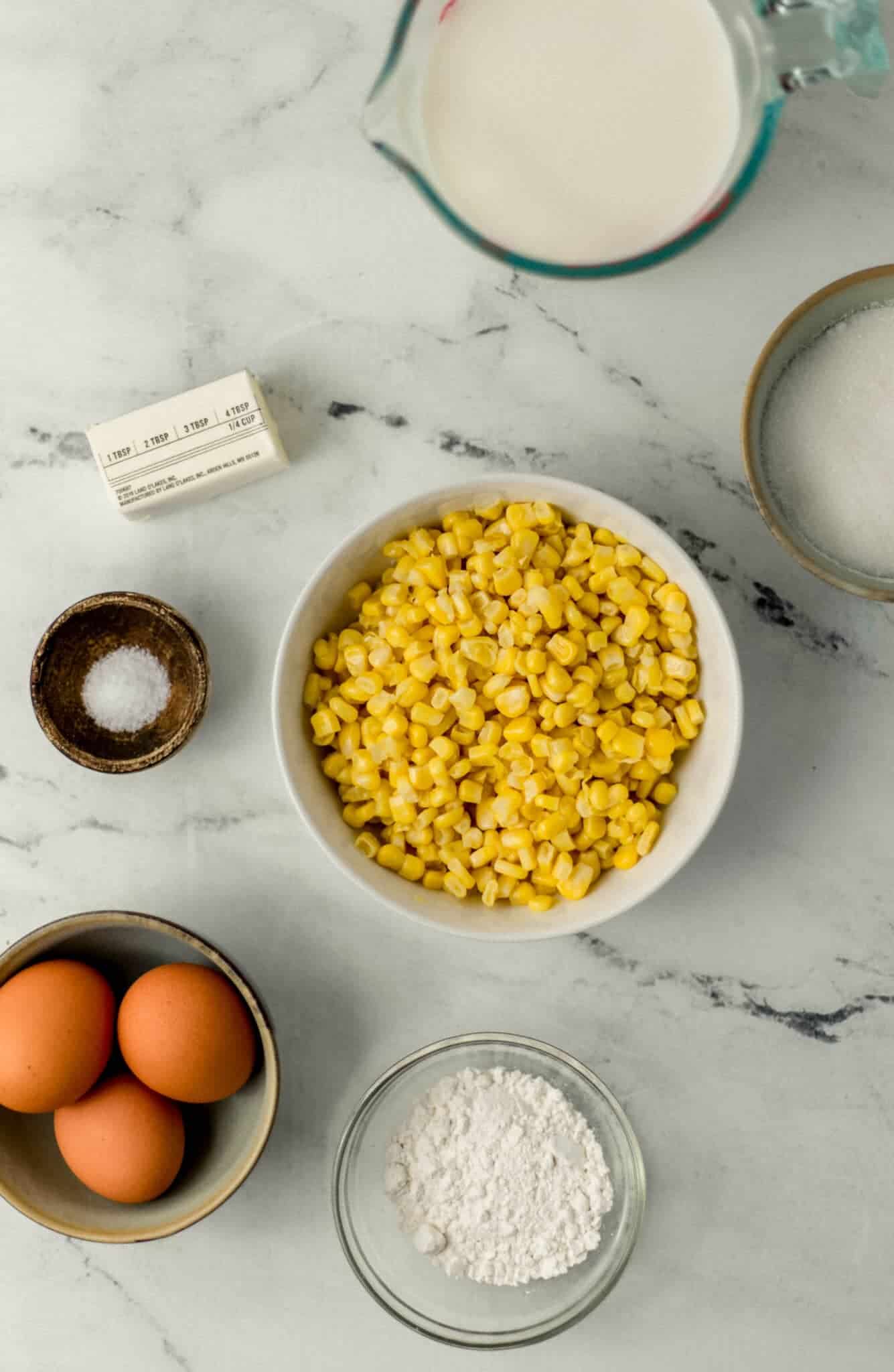 overhead view of ingredients needed to make pudding in separate bowls on marble surface 