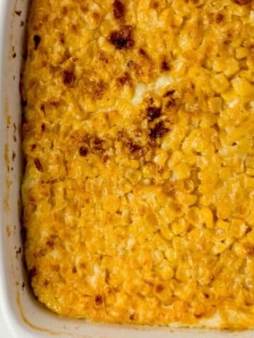Close up view of finished corn pudding in white baking dish.