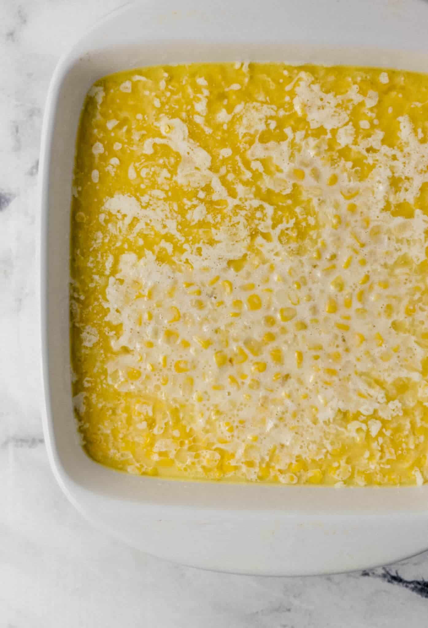 corn pudding mixture added to square baking dish with melted butter 