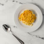 overhead view of finished serving of pudding on small white plate by a spoon