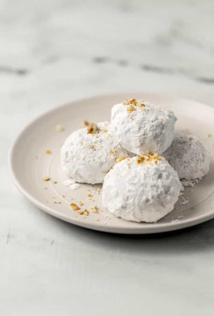 close up side view of finished pecan tea cakes on white plate topped with chopped pecans