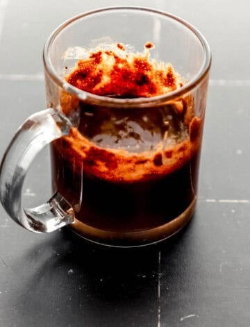 Brownie ingredients mixed in glass mug.