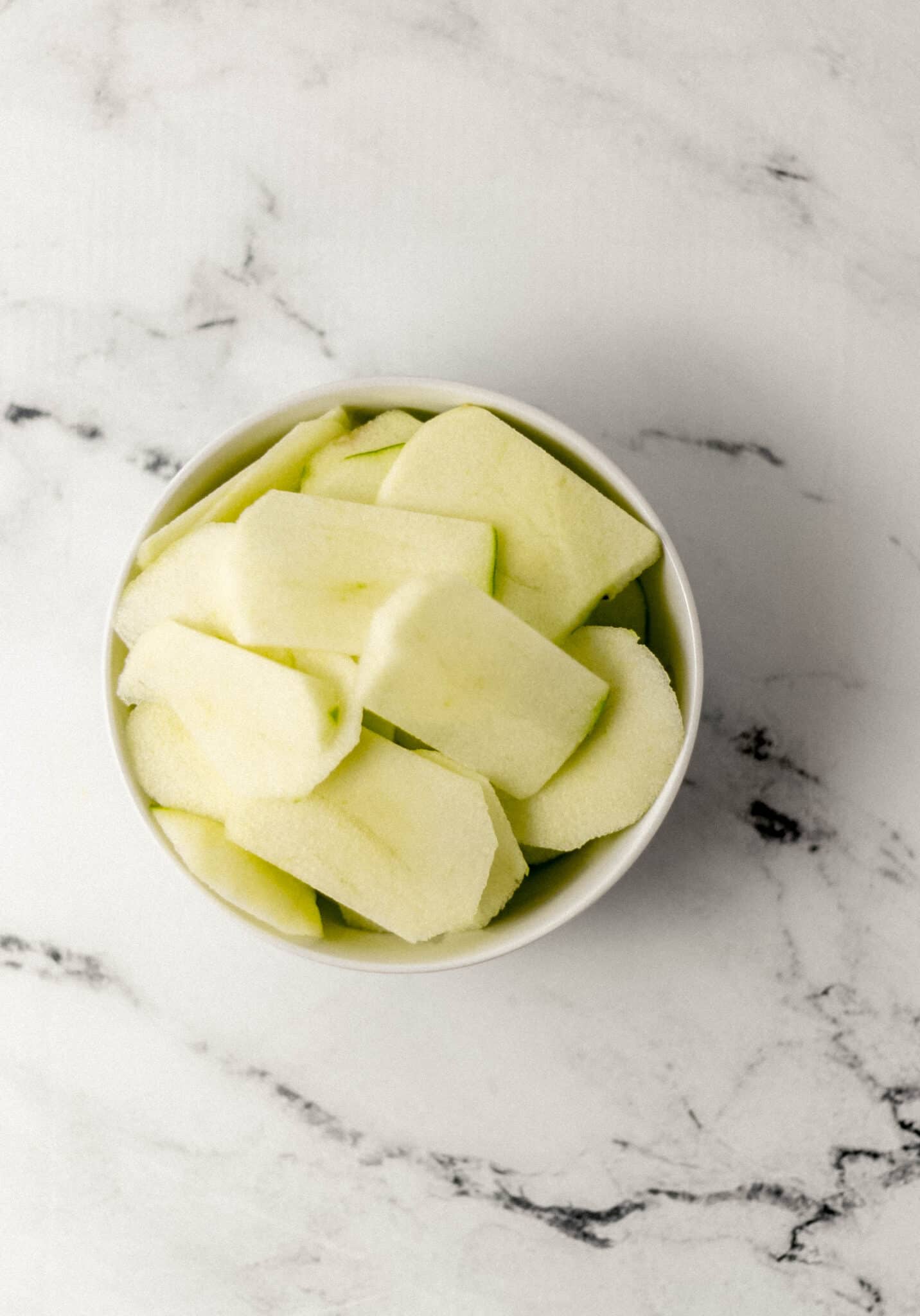 overhead view of apple slices in white bowl 